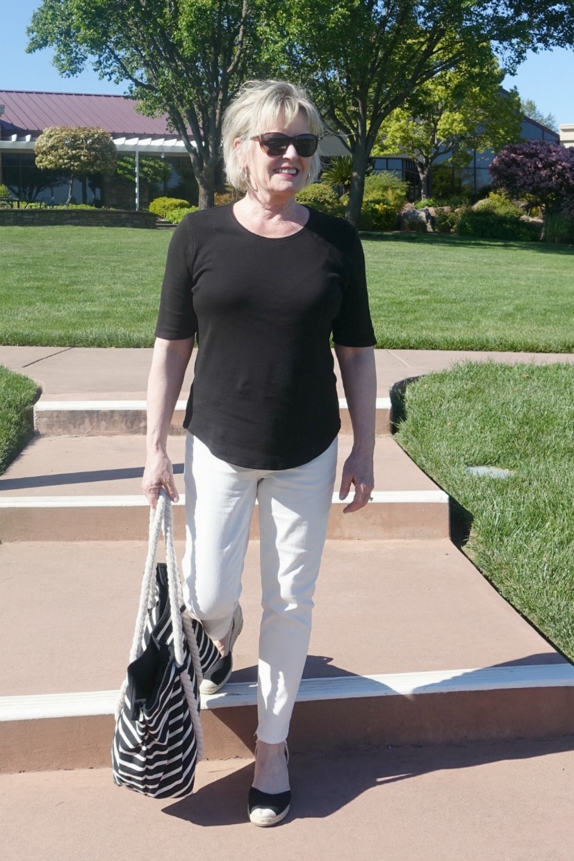 Jennifer from A Well Styled Life wearing black and cream colored outfit with striped tote and espadrilles