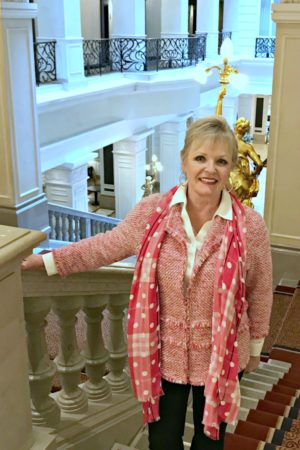 Jennifer Connolly of A Well Styled life on grand staircase of Corinthia Hotel in Budapest wearing Chico's blazer and