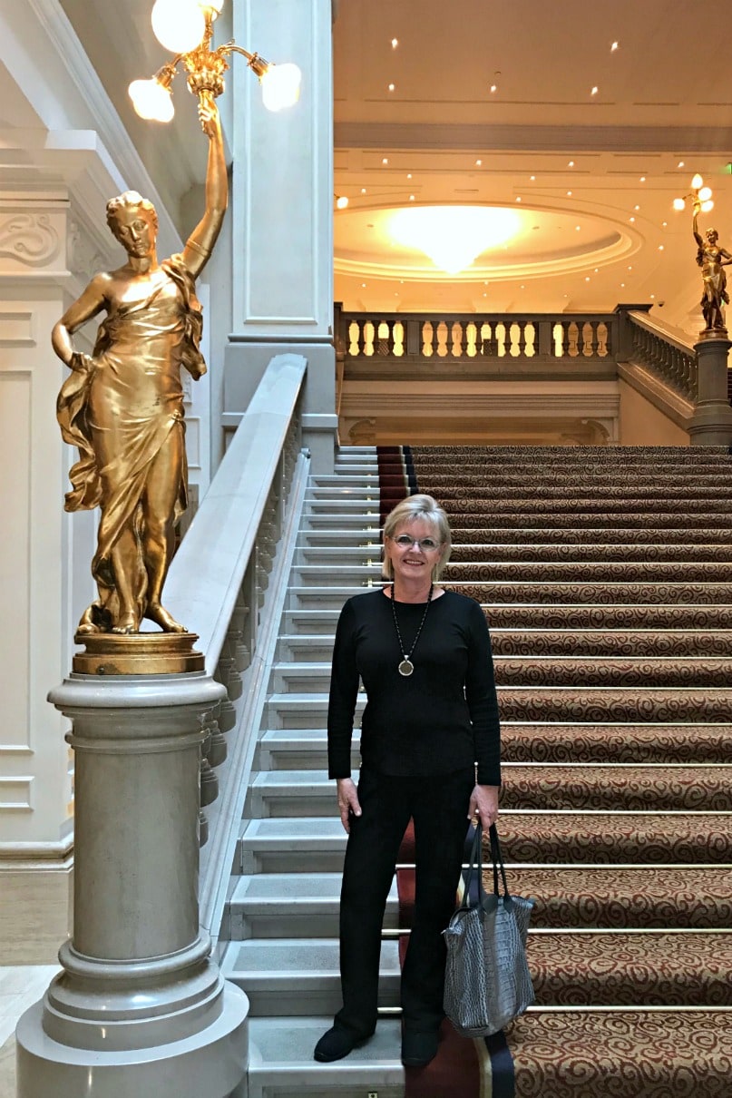 Jennifer Connolly of A Well Styled Life wearing black on the grand staircase of the Corinthia Hotel in Bucharest