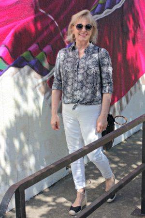 Jennifer Connolly of A Well Styled Life wearing casual outfit of white jeans, with black and white snakeskin shirt and black espadrilles