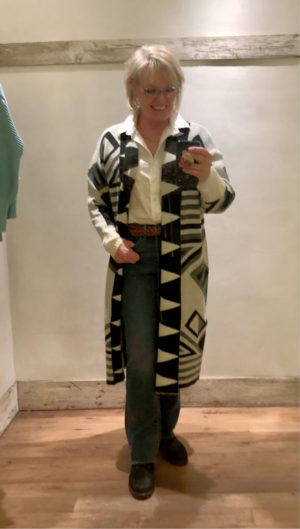 woman trying on patterned sweater coat in anthropologie dressing room