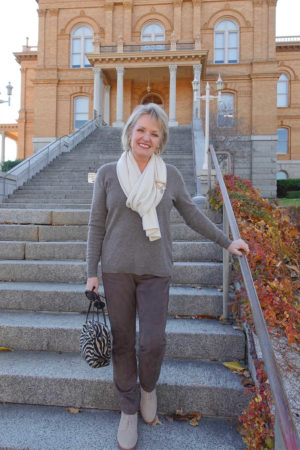 jennifer connolly of a well styled life wearing beige sweater and pants on stairs of old building