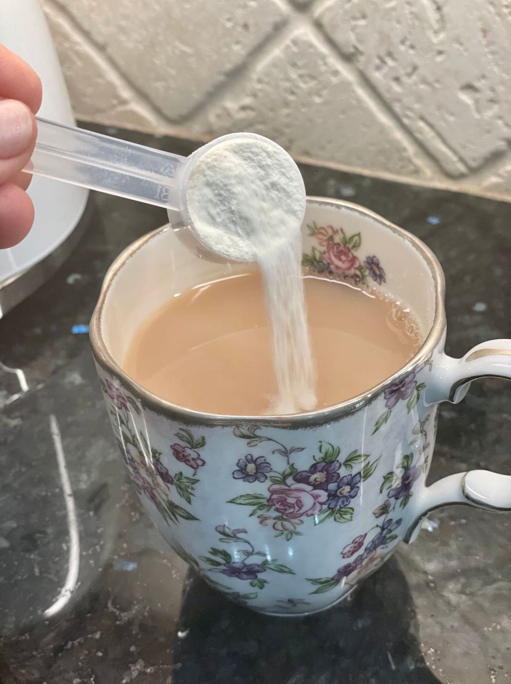 pouring collagen powder into cup of tea