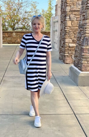 woman walking in navy and white striipe dress and white tennies