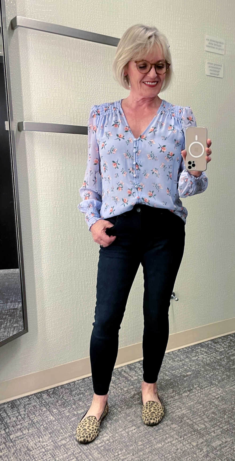 woman taking selfie wearing floral blouse and skinny jeans
