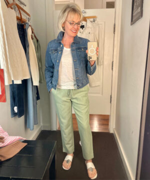 woman wearing white tee, green pants and denim jacket in dressing room