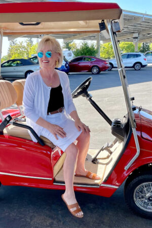 woman wearing white sitting in red golf cart