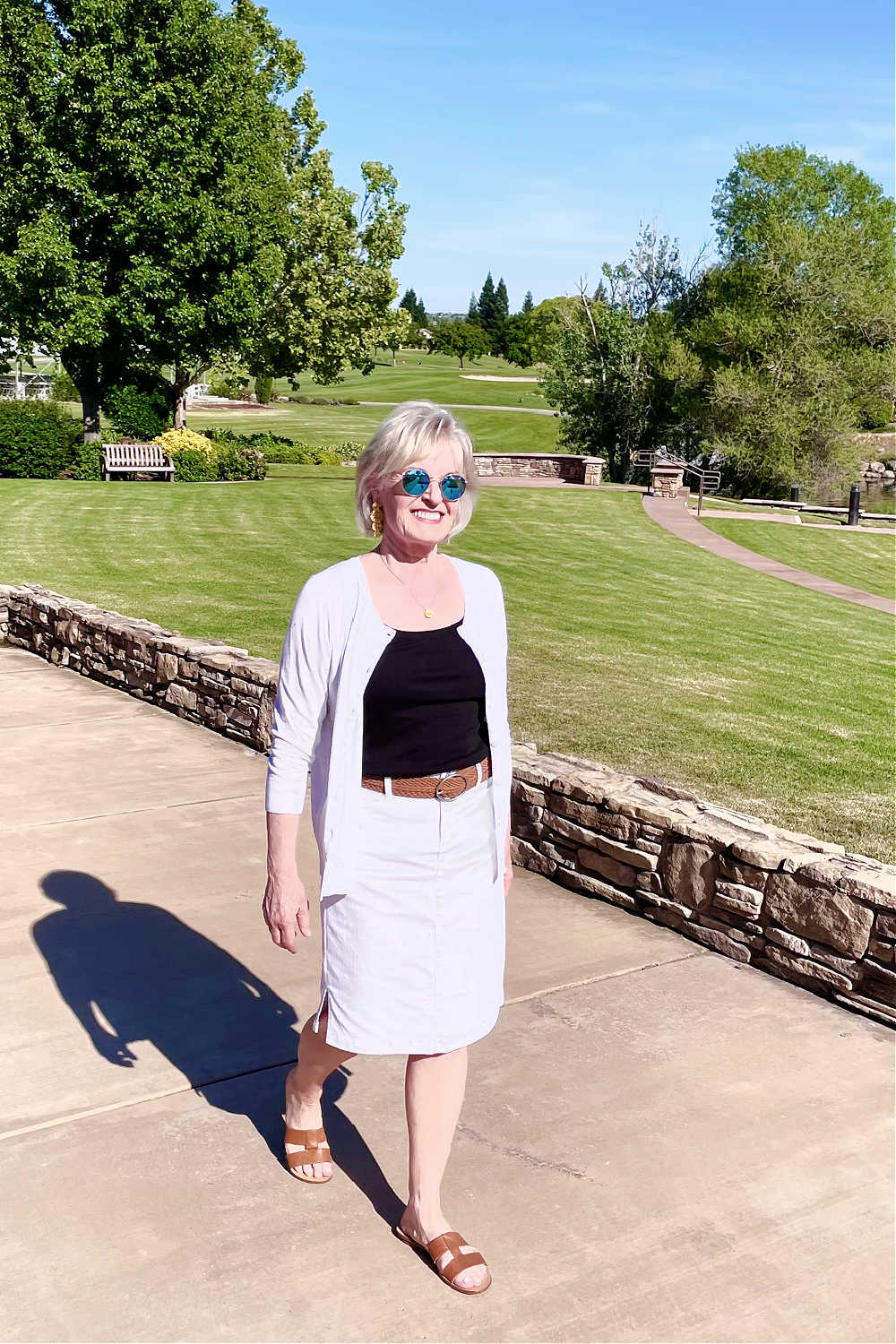 woman walking on golf path wearing white skirt and cardigan