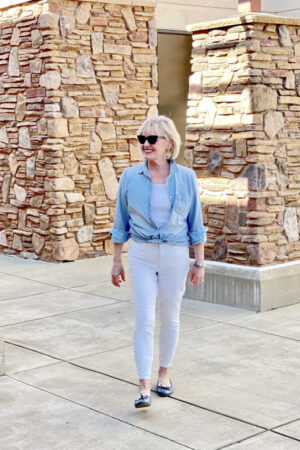 woman walking toward to wearing chambray shirt white jeans and blue shoes