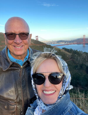 man an woman smiling into camera with golden gate bridge behind them