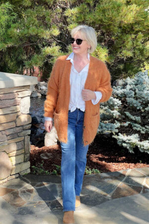 orange cardigamn with blue jeans and chelsea boots on blonde woman