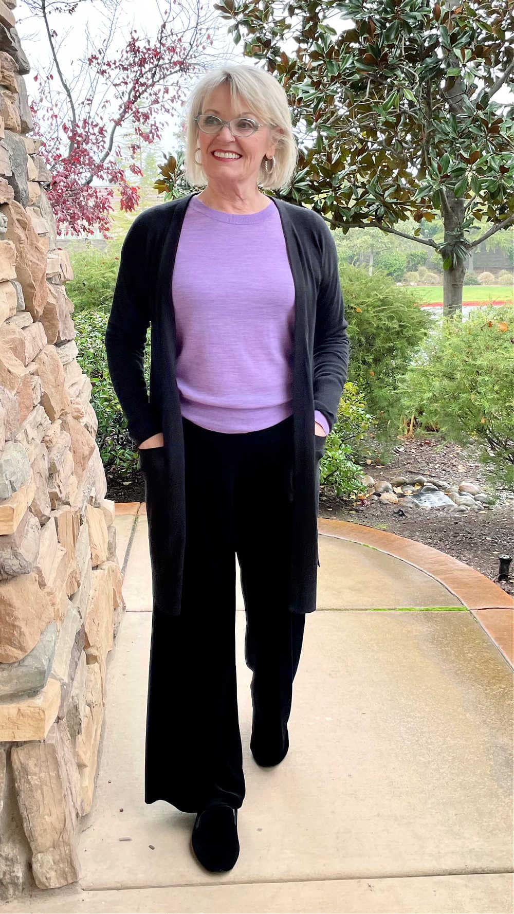 blonde woman walking in black pants and purple sweater