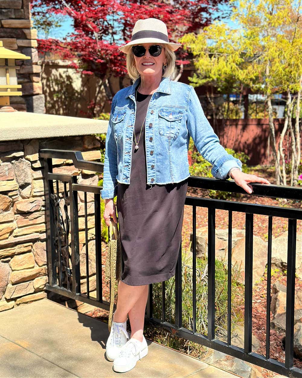 woman wearing denim jacket over t-shirt drss and white sneakers