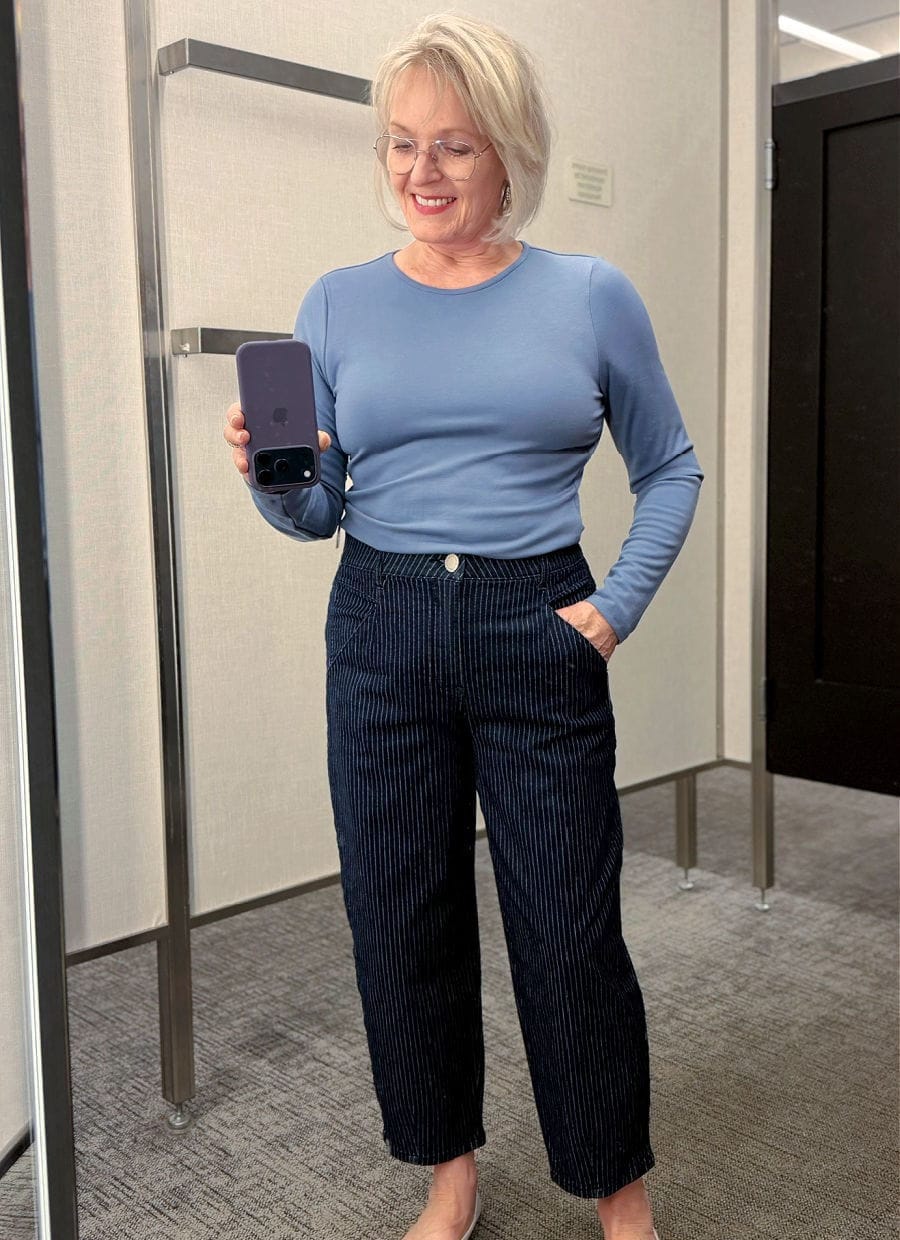 woman in dressing room tryin on barrel leg jeans trend for 2026