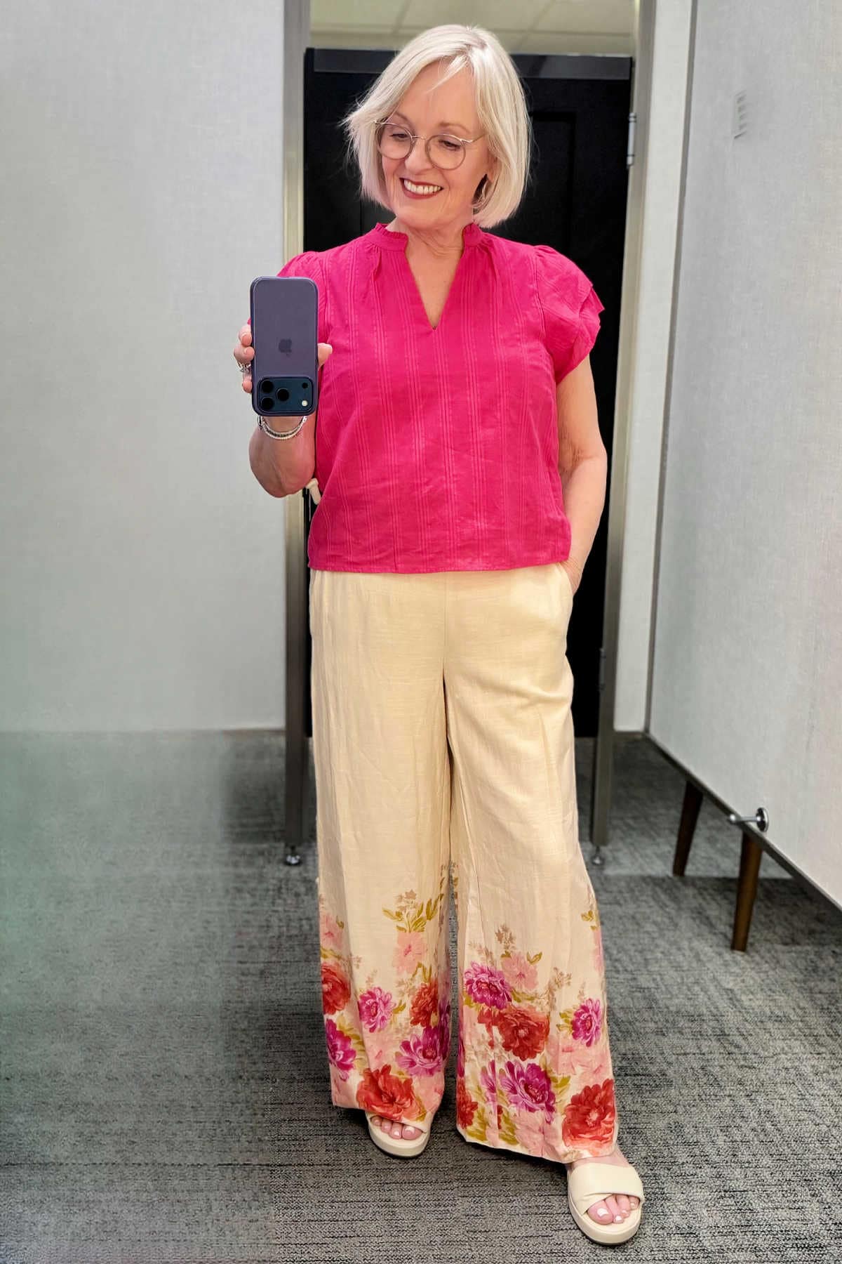 Stylish summer wide-leg pants outfit for women over 50 with patterned trousers and a bright pink flutter sleeve top.