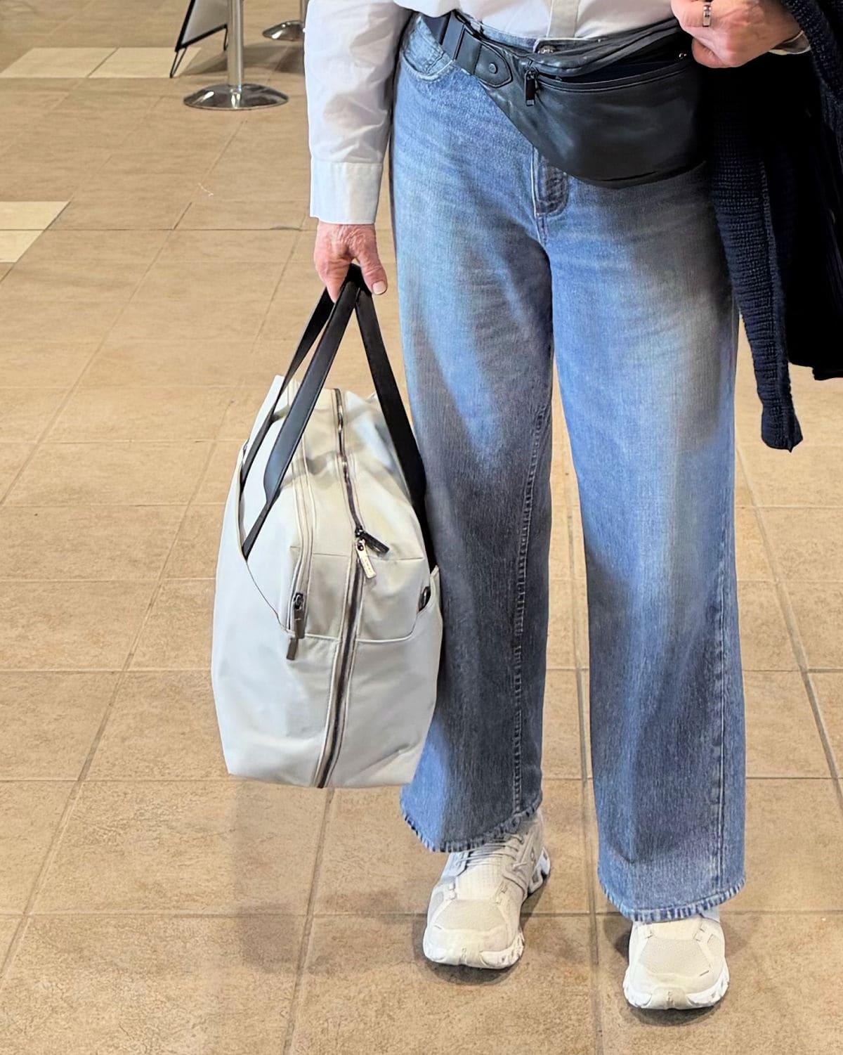 WOMAN AT AIRPORT CARRYING AWAY OVERNIGHT BAG FOR AIRPLANE